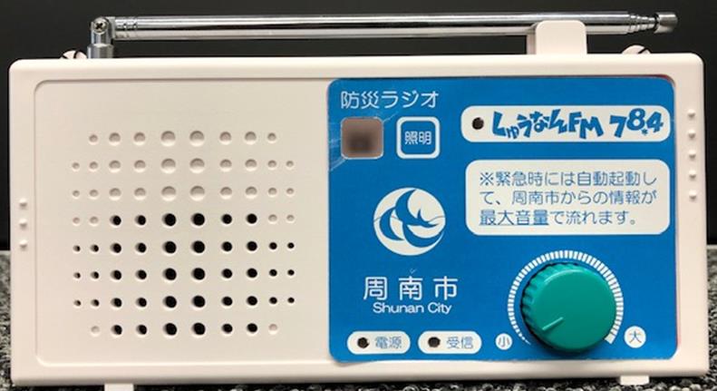 周南市防災ラジオ。青いパネルにしゅうなんFM 78.4の表示と、緑色の音量つまみがある